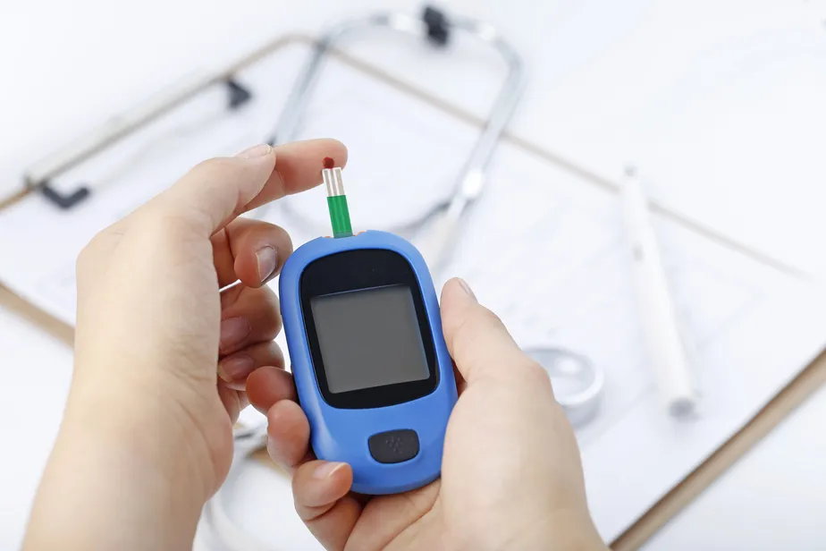 hand-holding-a-blood-glucose-meter-measuring-blood-sugar-the-background-is-a-stethoscope-and-chart-file